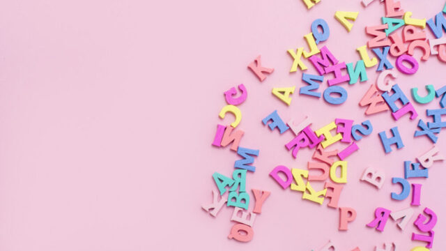 Many multicolored wooden letters on a pink background. toy letters. english alphabet. View from above. Flat lay. Copy space for text