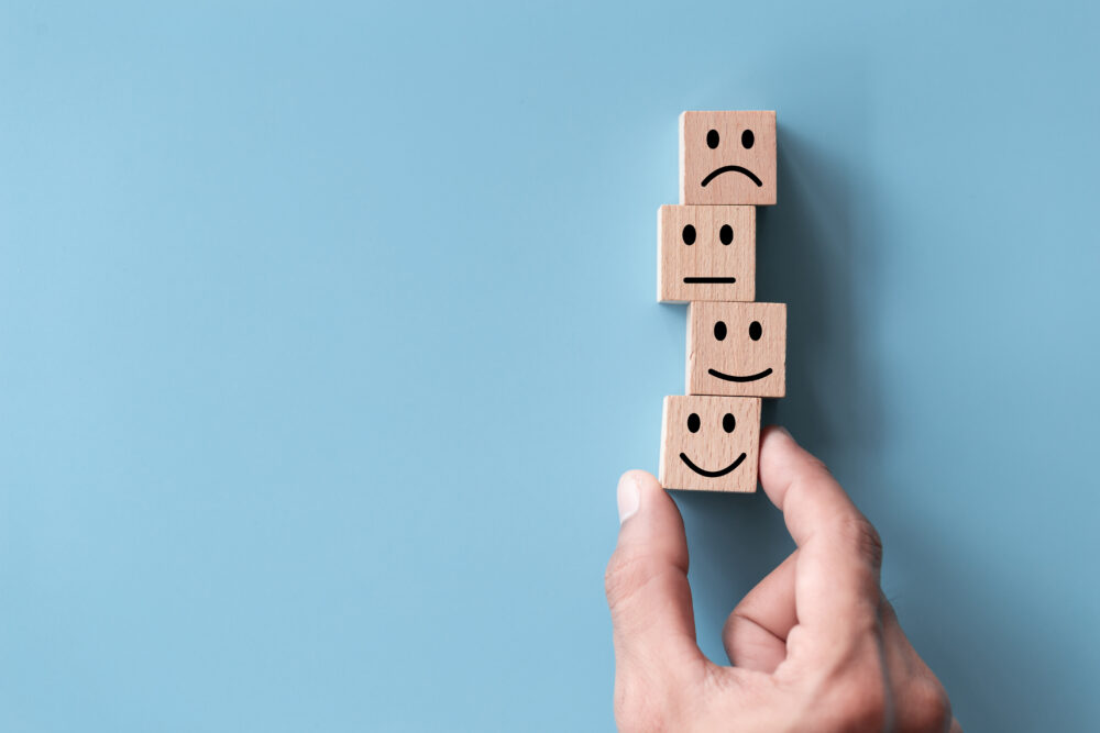 Close up top view customer hand choose smiley face on wood cube,