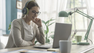 Young woman sitting at desk and watching videos online