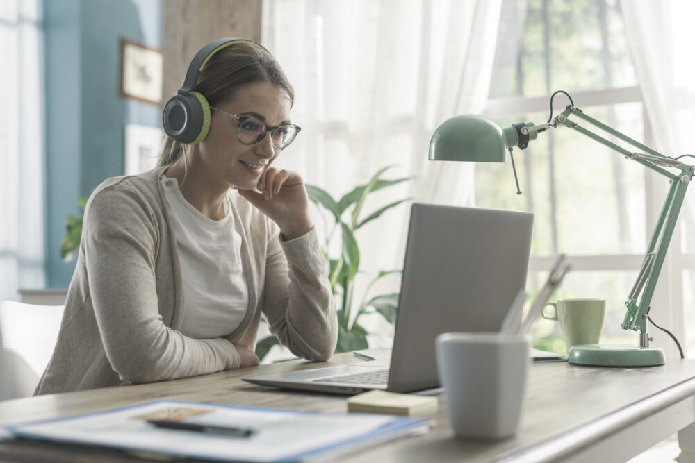 Young woman sitting at desk and watching videos online